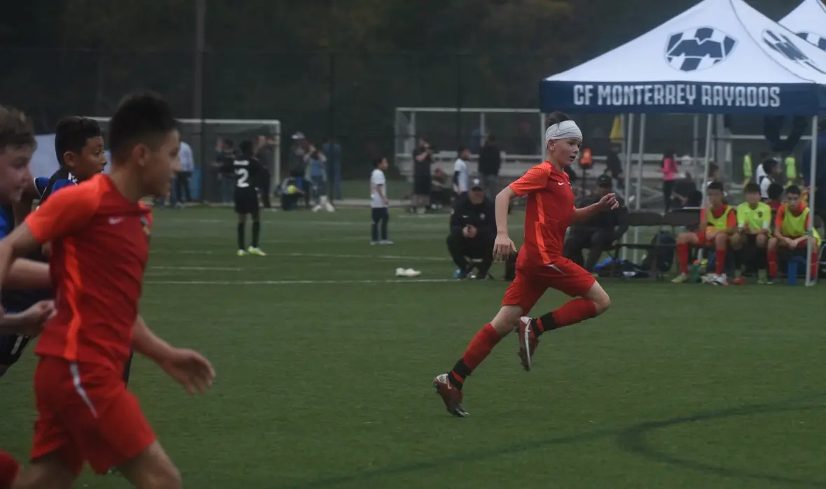 Daylen Hammon in orange Real Colorado kit sprinting past defenders at Copa Rayados CF Monterrey tournament November 2022