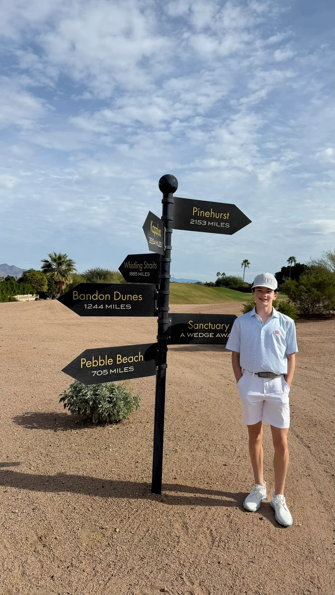 Daylen Hammon standing next to golf course directional sign pointing to Pebble Beach, Pinehurst, Bandon Dunes and more