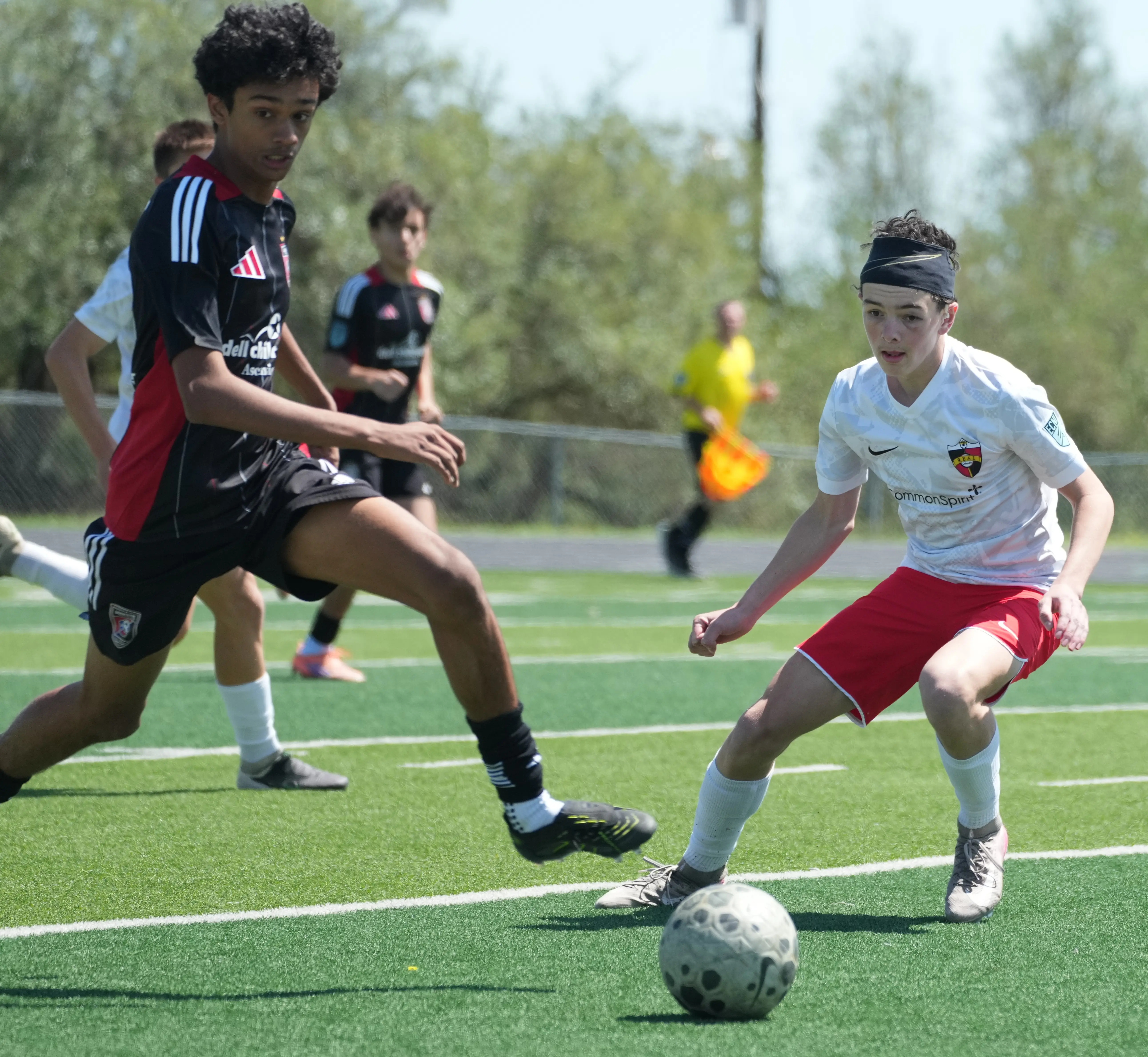 Daylen Hammon in white Real Colorado kit shielding ball from defender in black and red kit