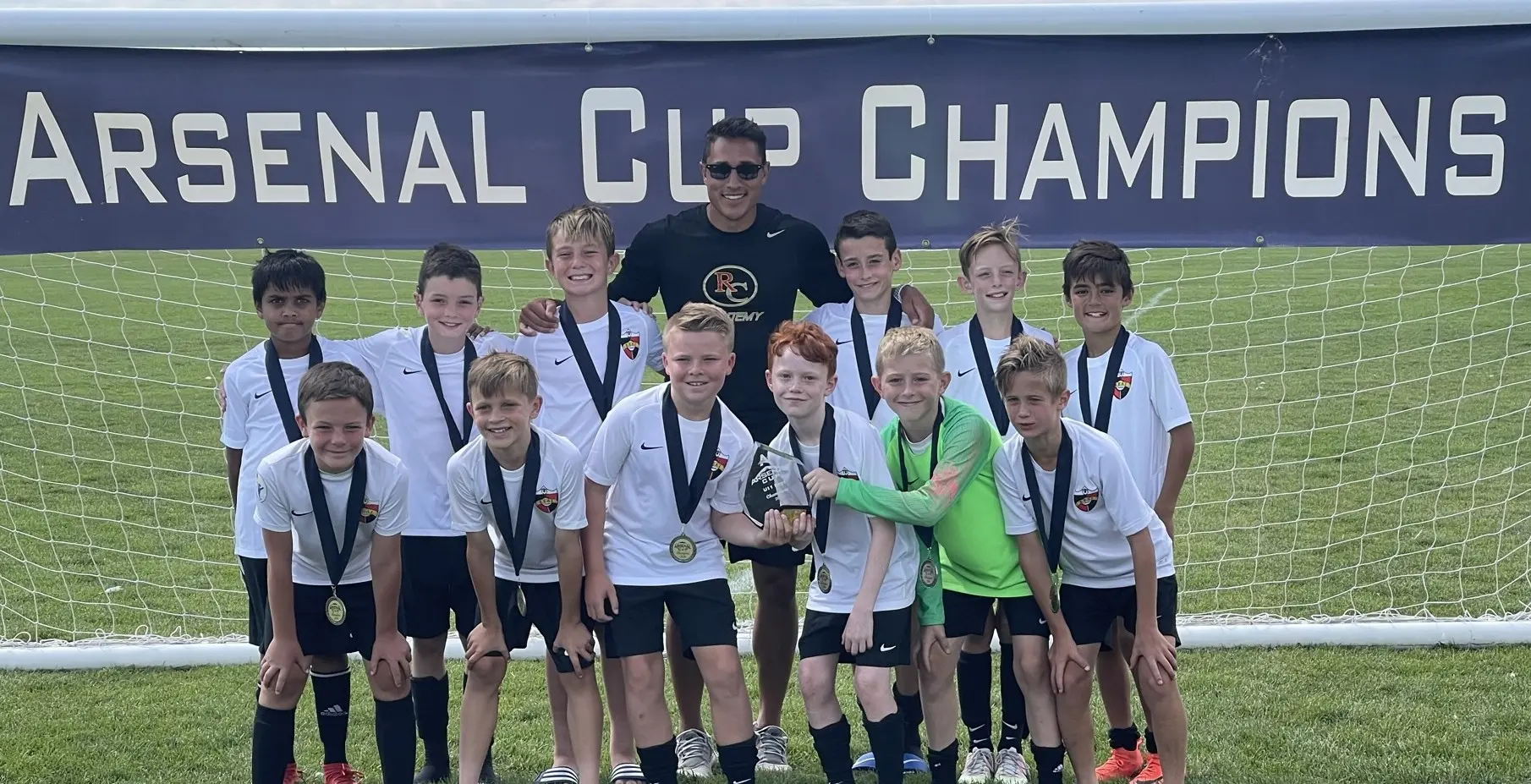 Real Colorado Academy Arsenal Cup Champions team photo in white kits with coach