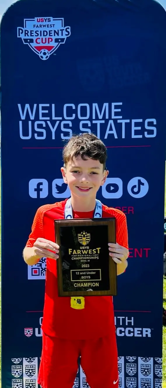 Daylen Hammon holding USYS Farwest Regional Championships 2023 champion plaque in front of Welcome USYS States banner in Boise, ID