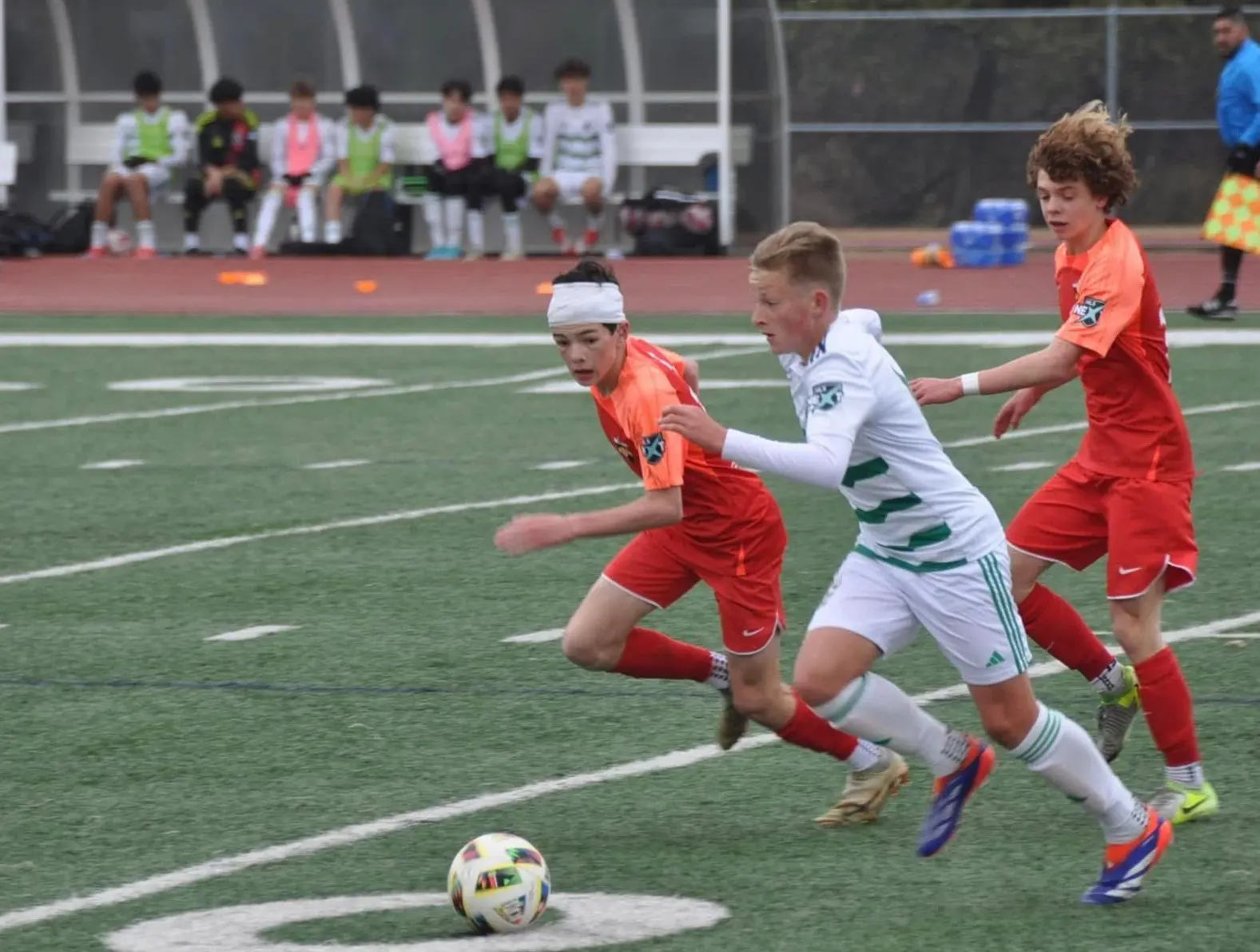 Daylen Hammon in red Real Colorado kit with white headband driving past opponent in white kit during MLS Next match Spring 2025