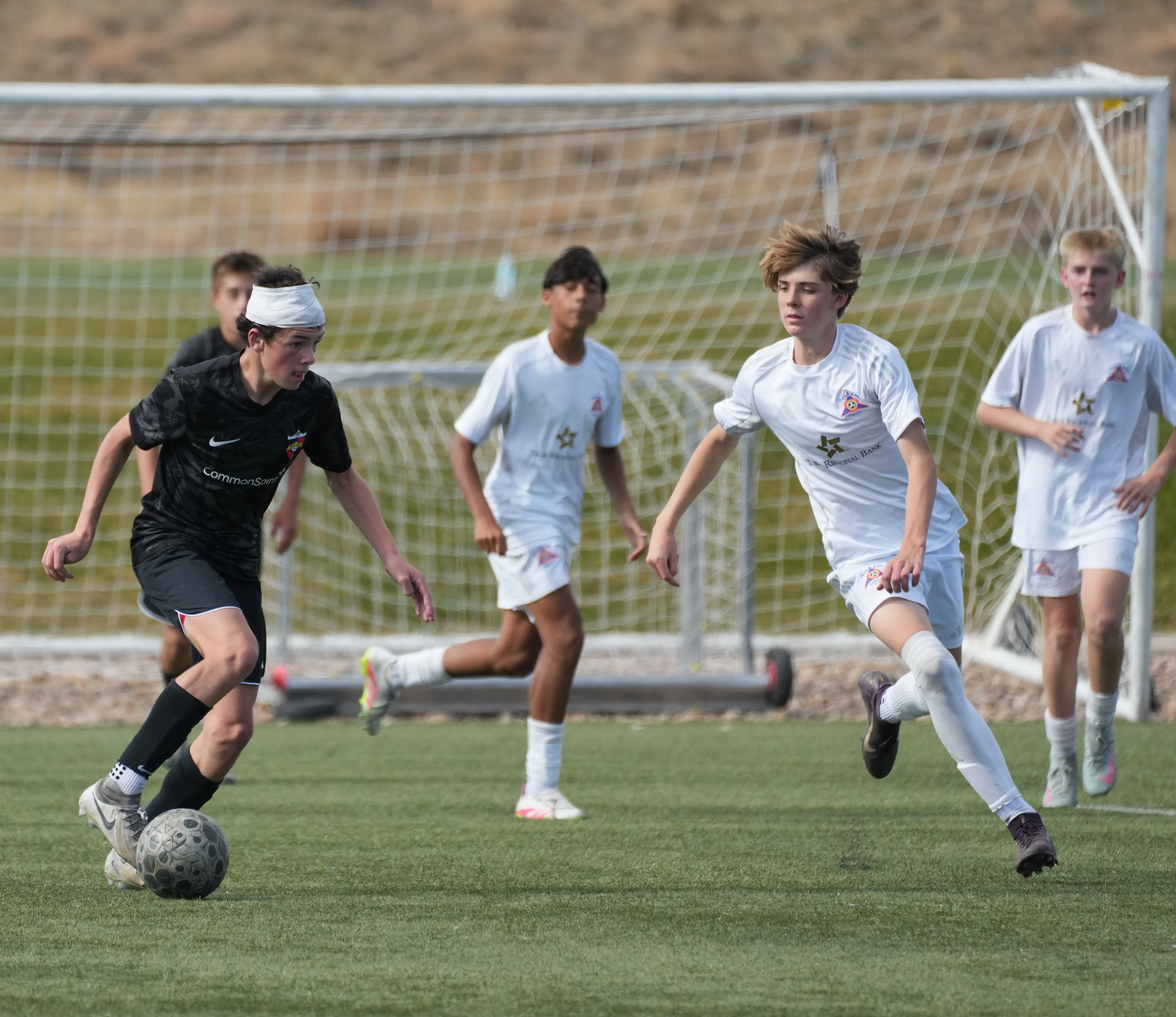 Daylen Hammon in black Real Colorado kit with white headband battling for the ball vs Solar Academy player in white kit, November 2025