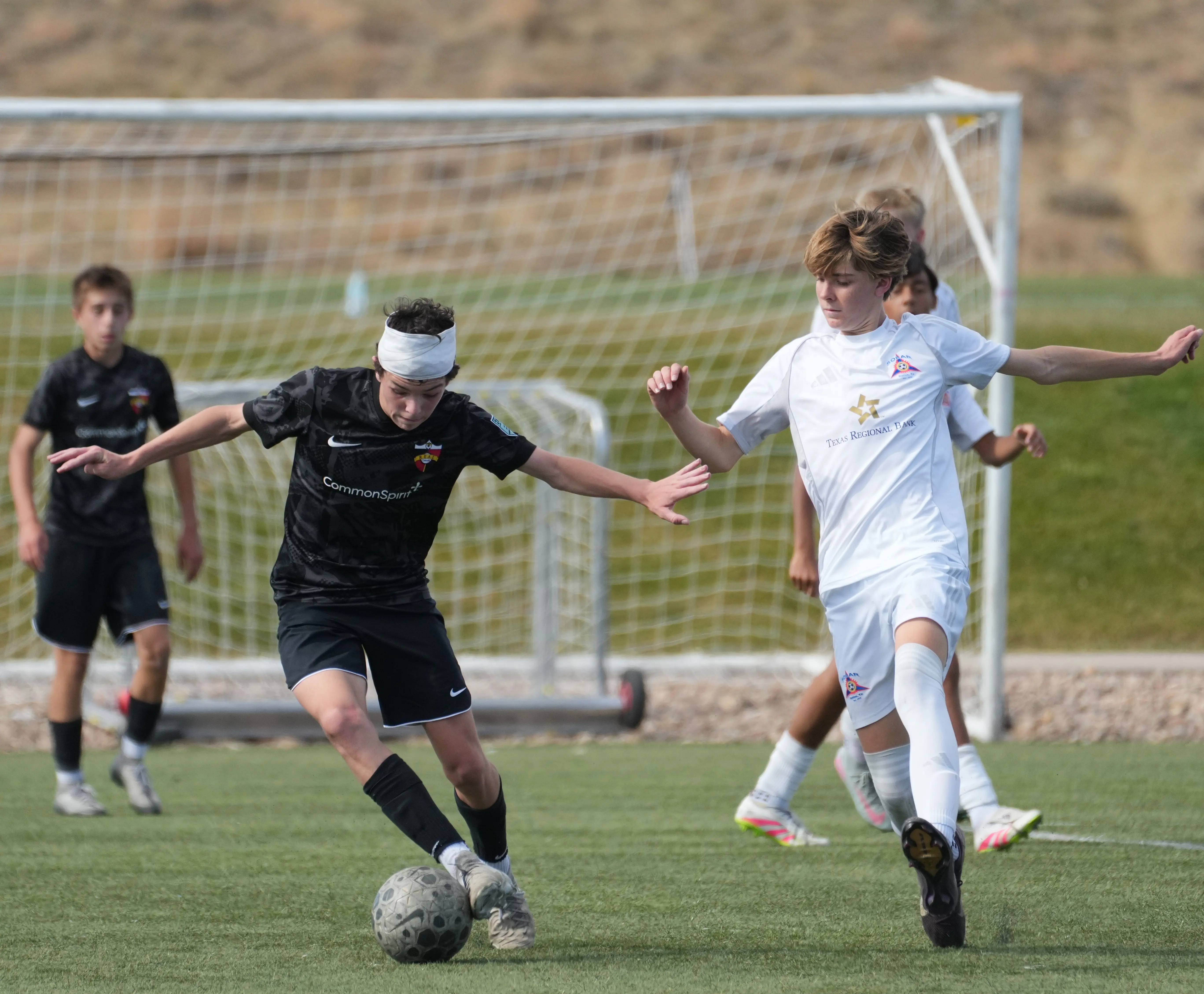 Daylen Hammon in black Real Colorado kit with white headband driving past Solar Academy defender in white kit, November 2025